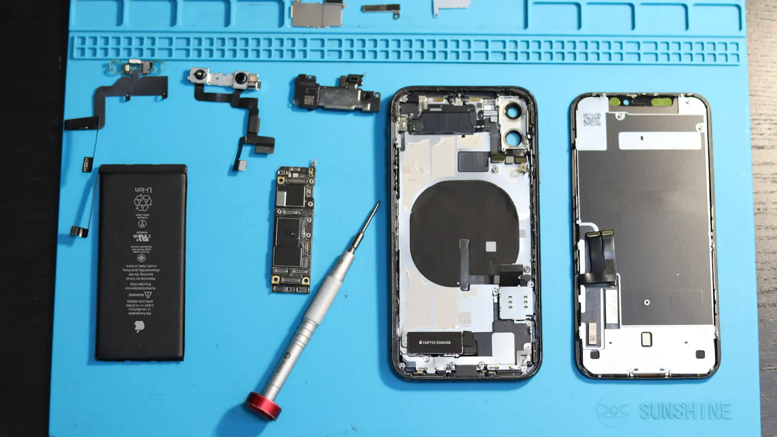 Celular desmontado na manta azul da bancada de reparo