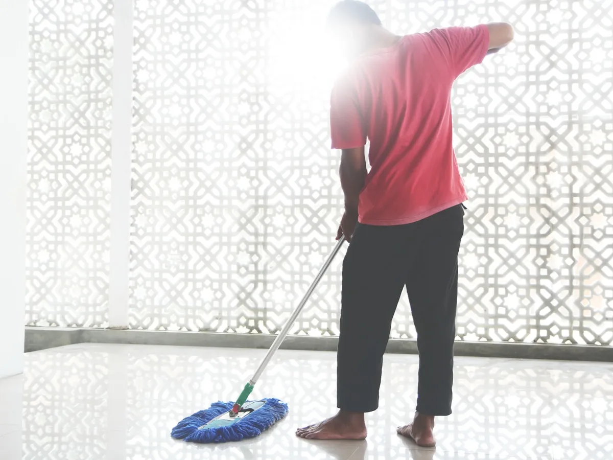 Profissional passando mop no piso espelhado do saguão